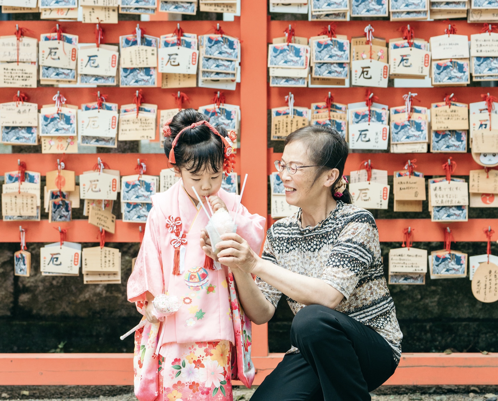 神社で祖母と孫が手をつなぐ七五三の家族写真