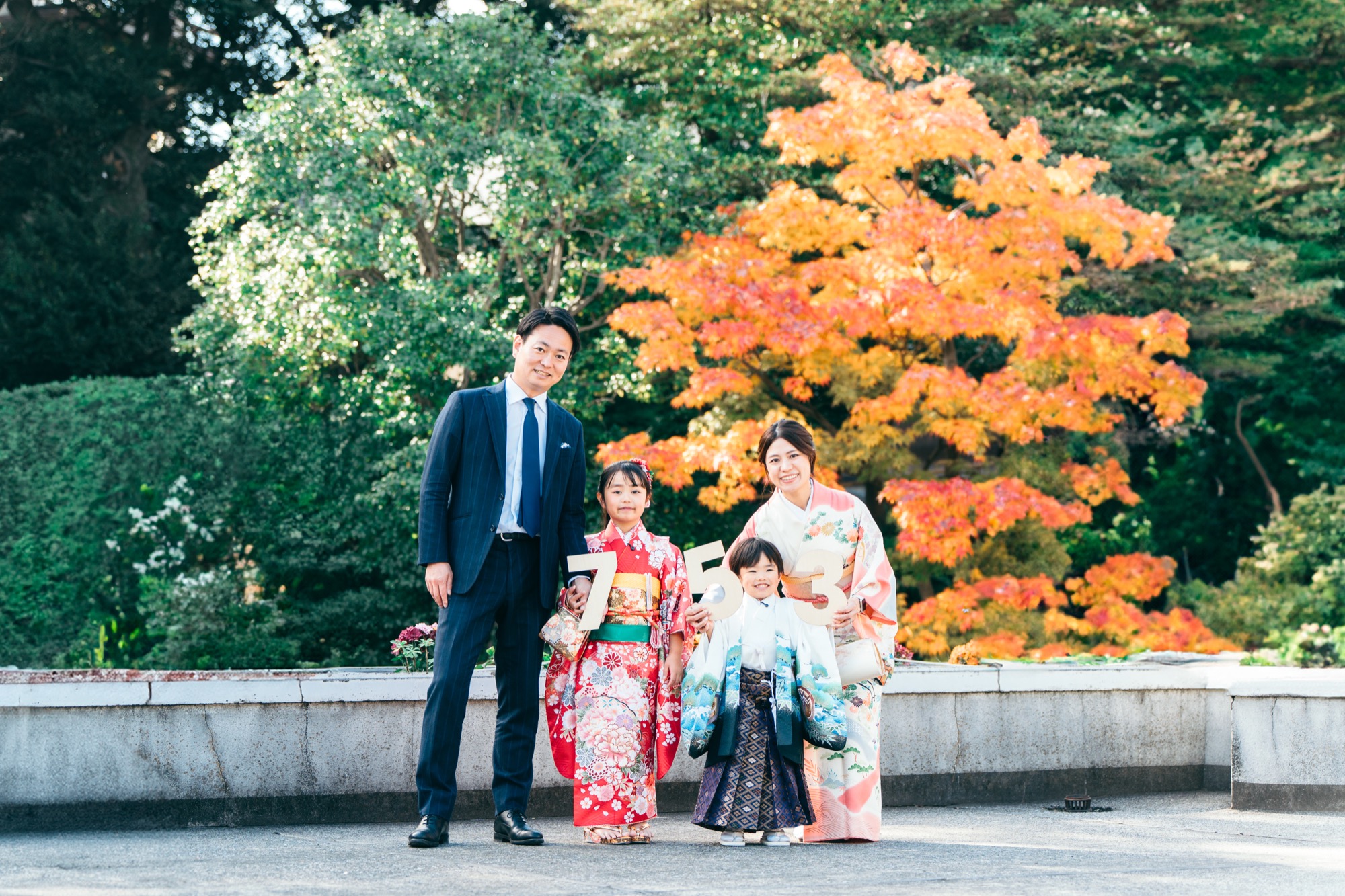 紅葉の前に立つ七五三のご家族