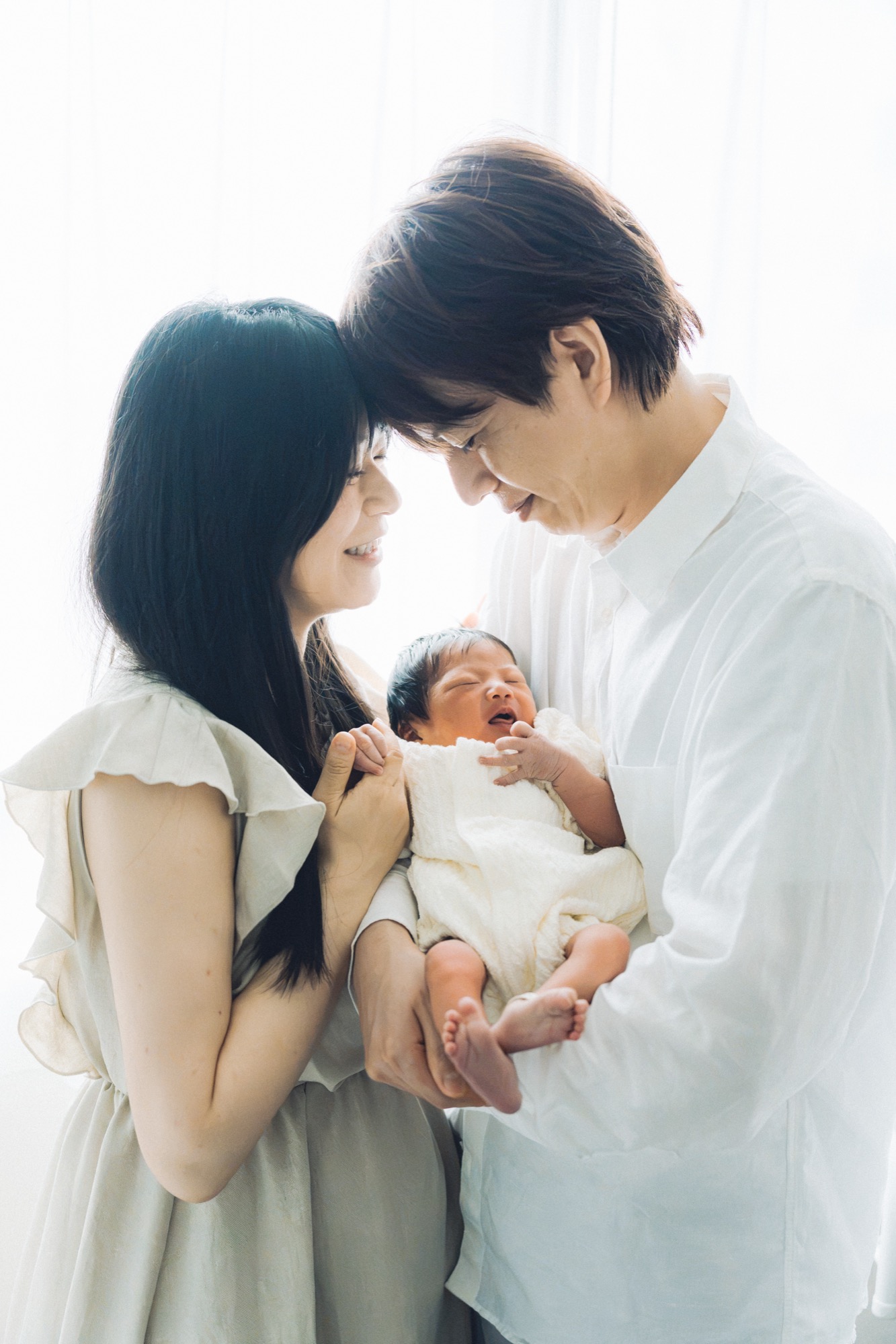 生まれたての赤ちゃんを抱いて微笑み合うご夫婦のニューボーンフォト