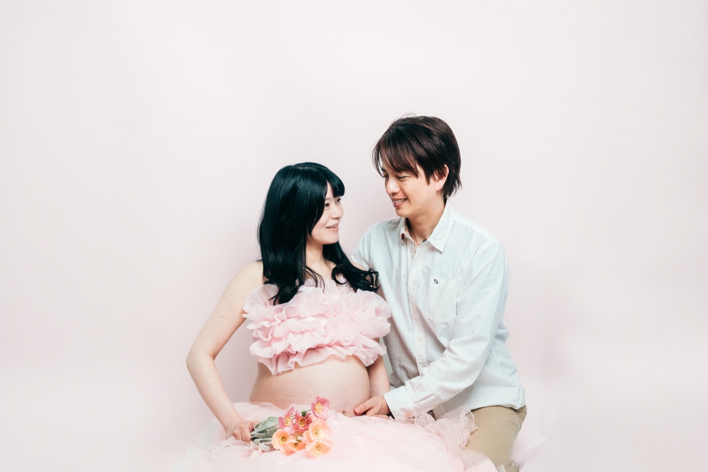 ピンクのマタニティドレスを着た妊婦さんとご主人 マタニティフォト スタジオ