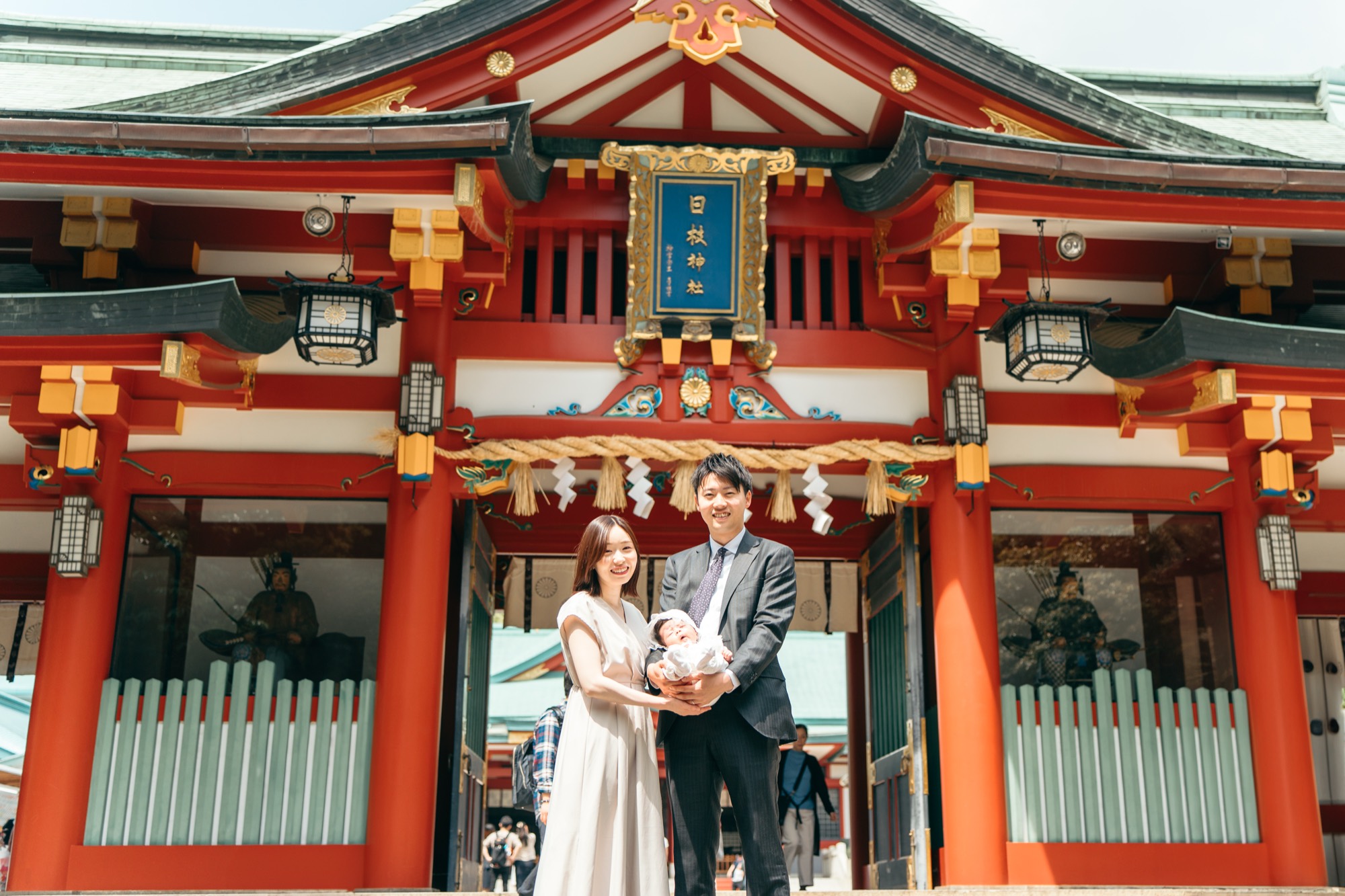 日枝神社 お宮参り 社殿前で祝い着の赤ちゃんを抱く家族