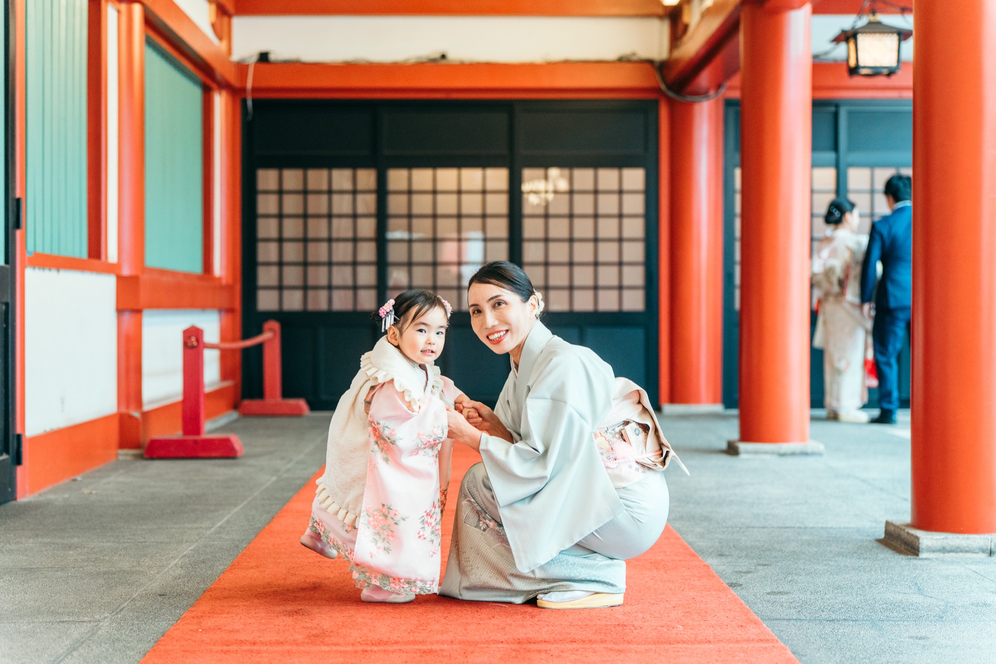 日枝神社の朱色の参道でママと寄り添う七五三・3歳の女の子