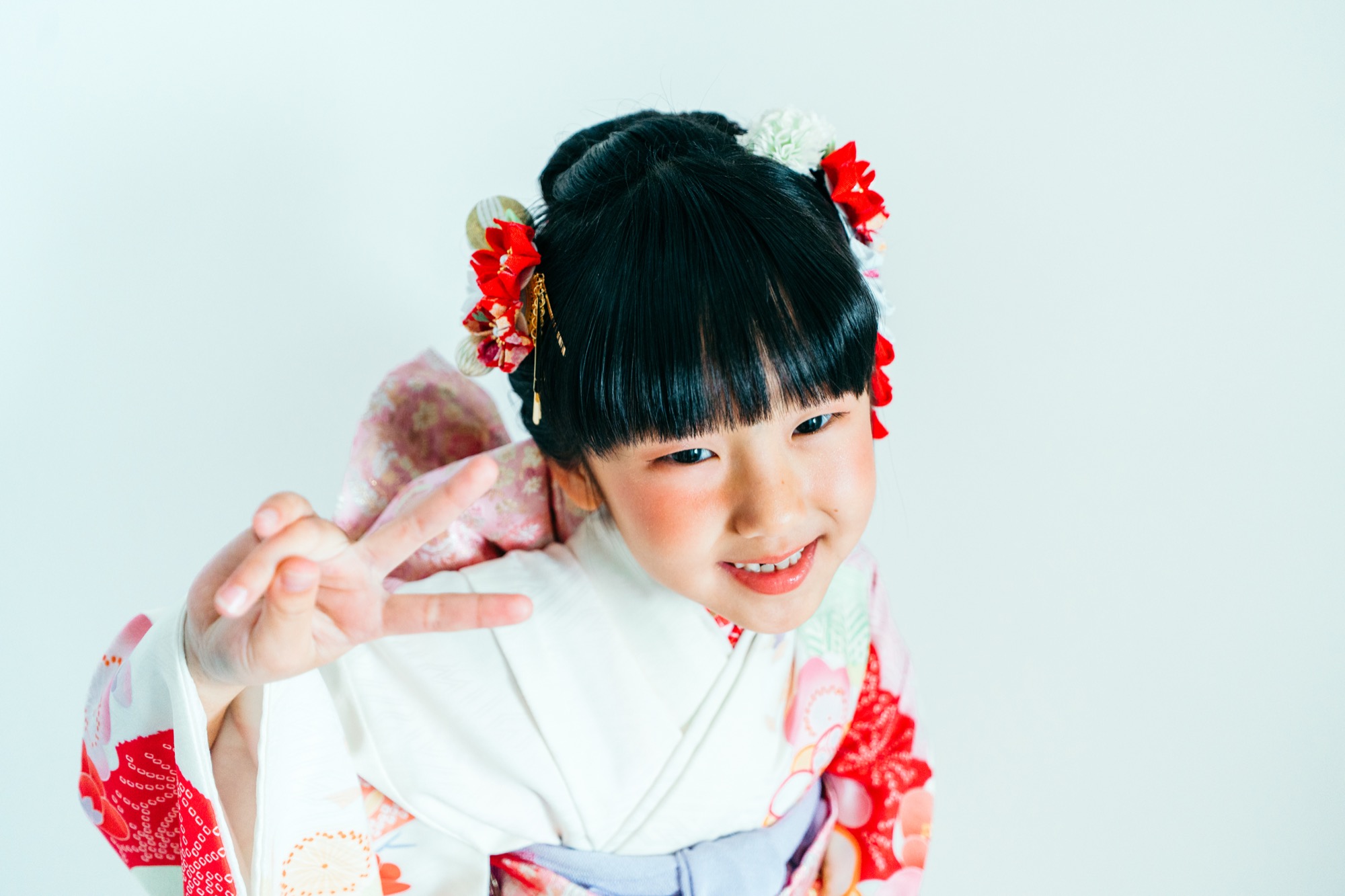 白い着物にピースサインで笑う七五三・7歳女の子のスタジオ撮影