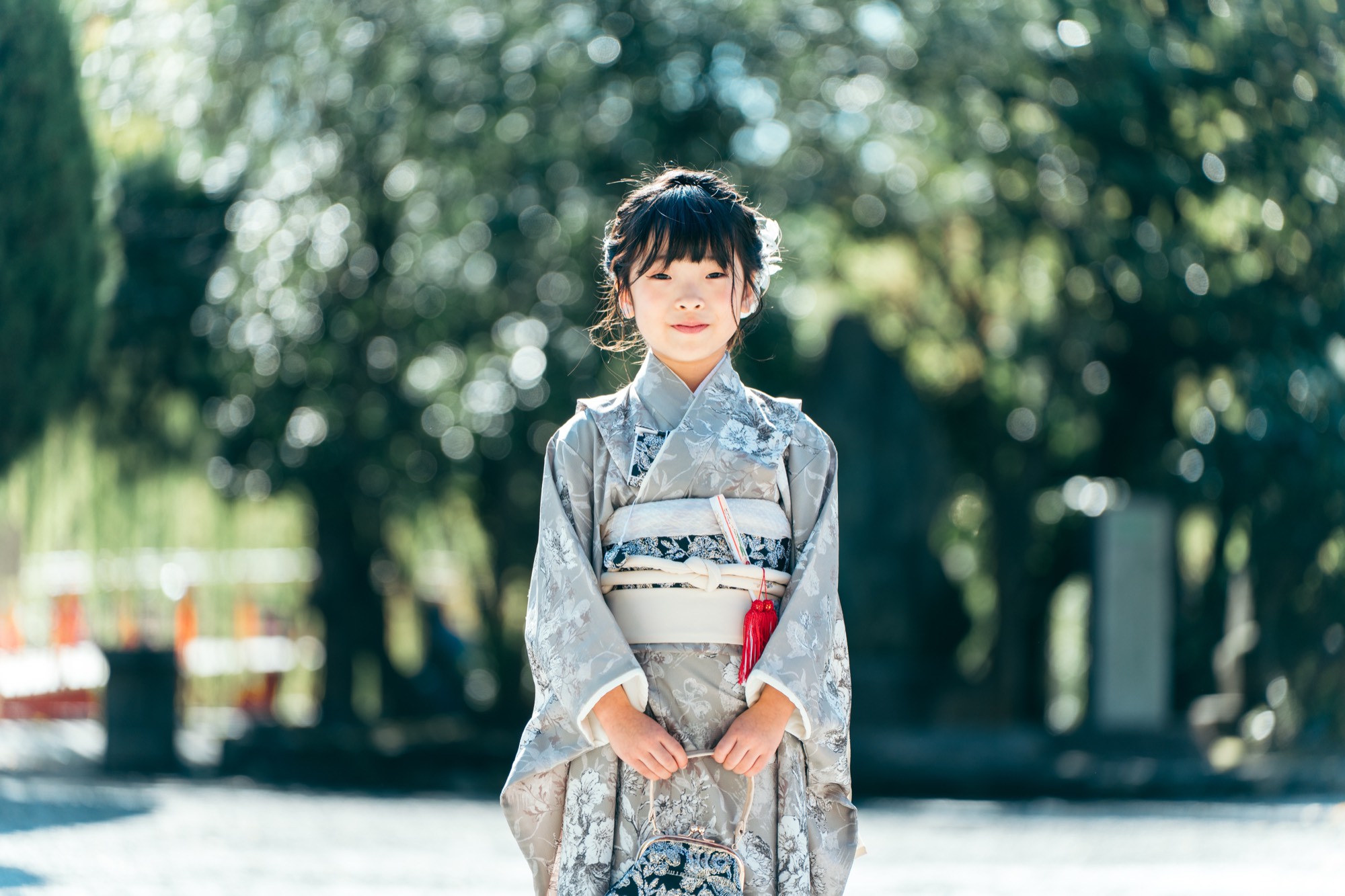 川崎大師の境内で、グレーの着物姿でほほえむ七五三・7歳の女の子