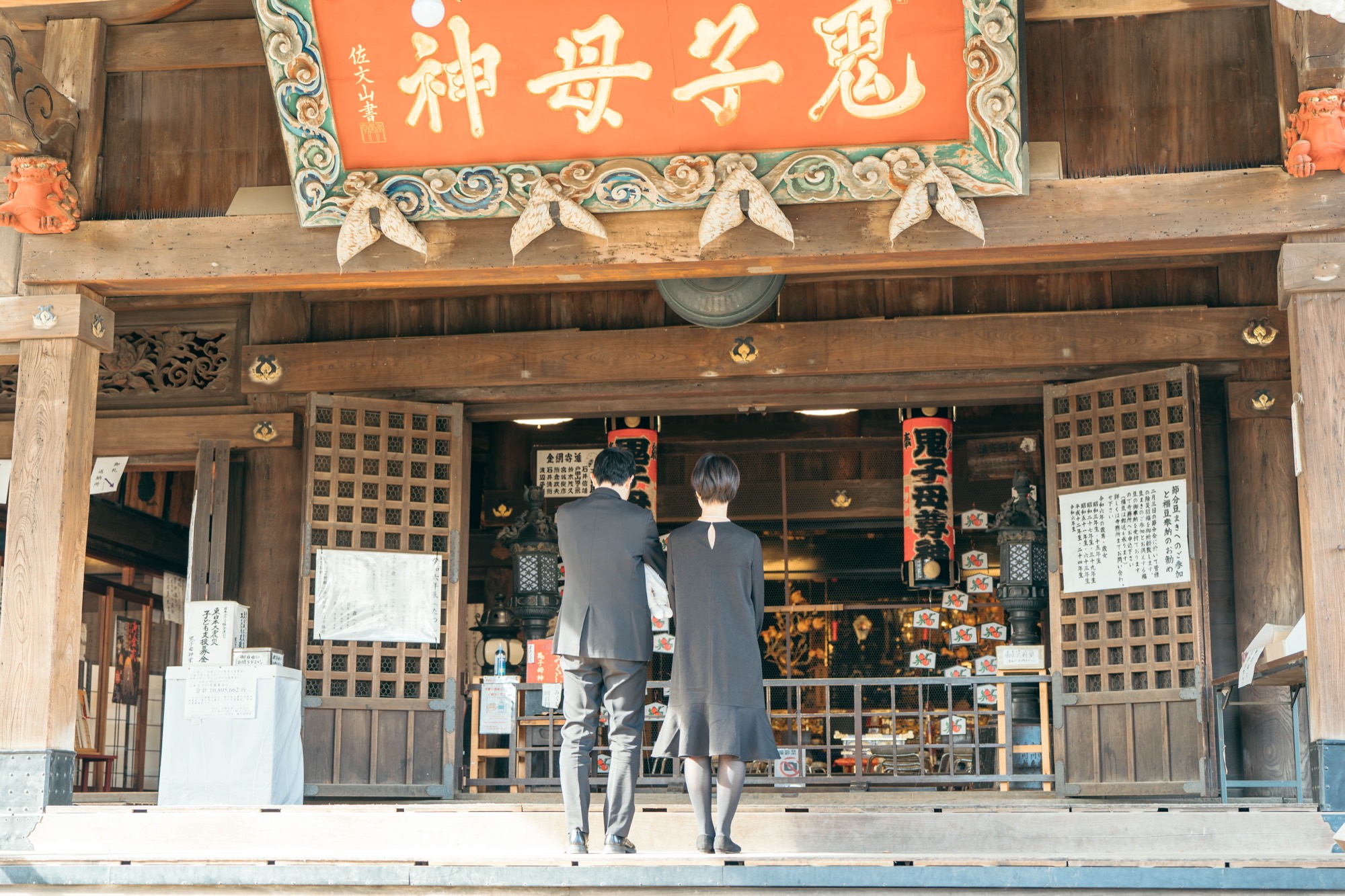 「鬼子母神」の本堂前でお参りするお宮参りのご夫婦(鬼子母神堂)