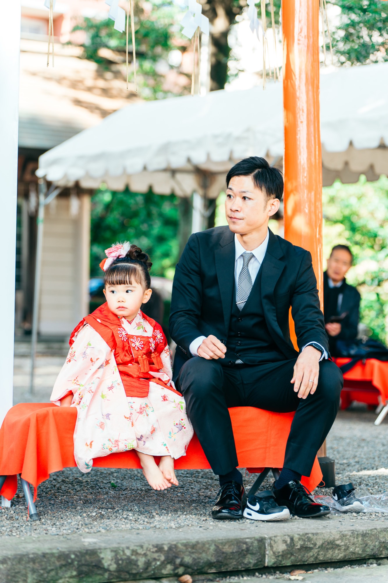 杵築大社の拝殿前のベンチで、お父様と並んで座る被布姿の3歳の女の子