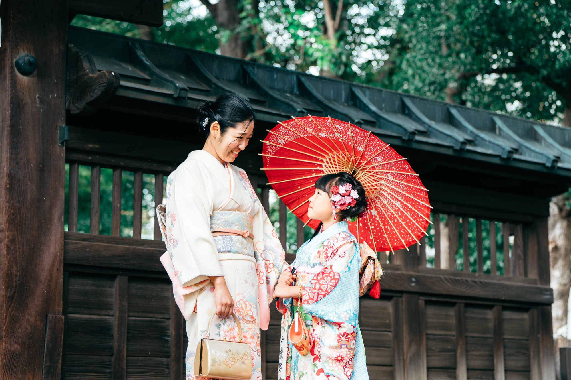馬込八幡神社の境内で、着物姿のお母様と和傘を持って笑い合う七五三の女の子