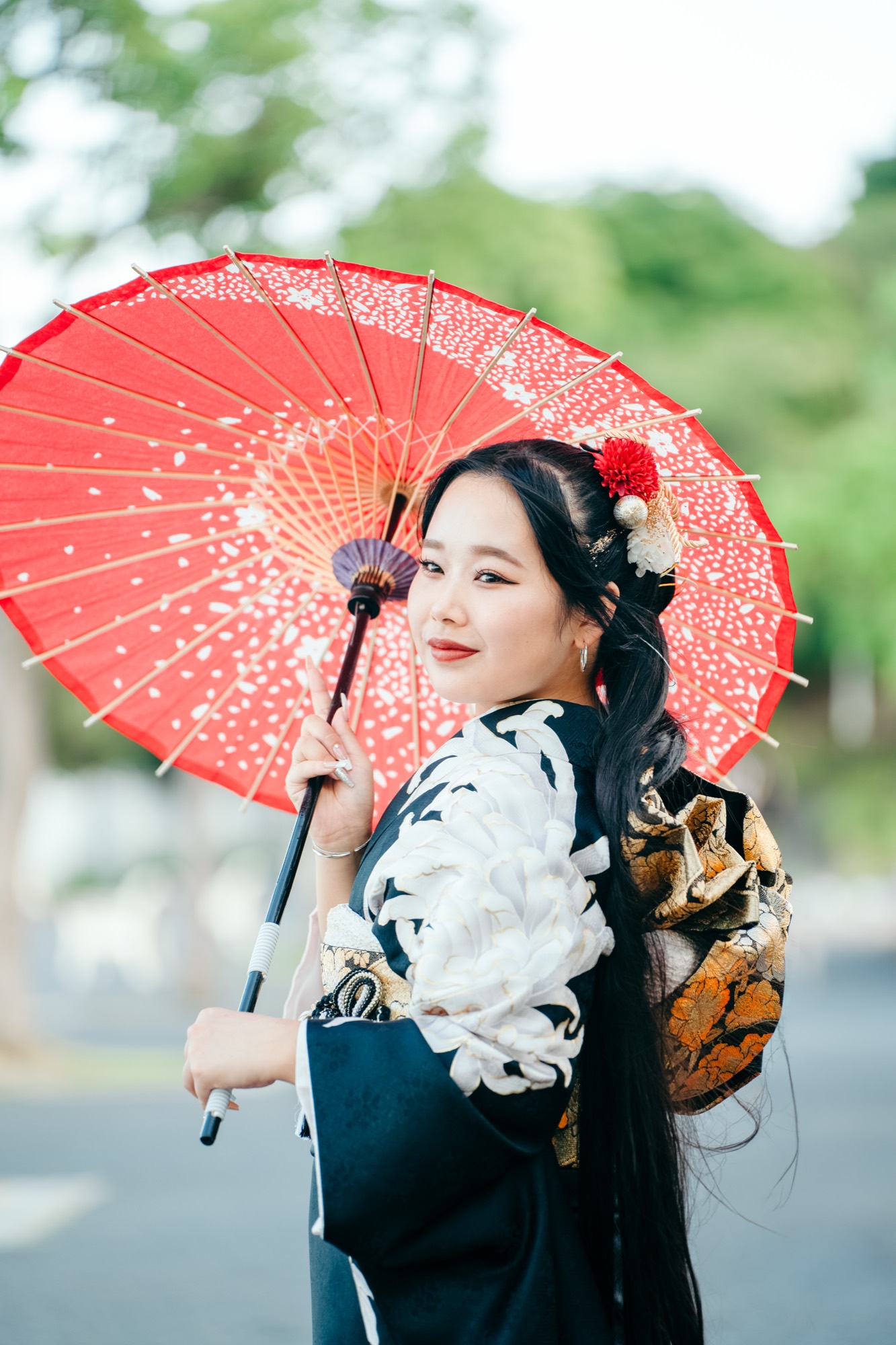 横浜・みなとみらいの並木道で、赤い和傘を差してほほえむ黒振袖の成人式前撮り