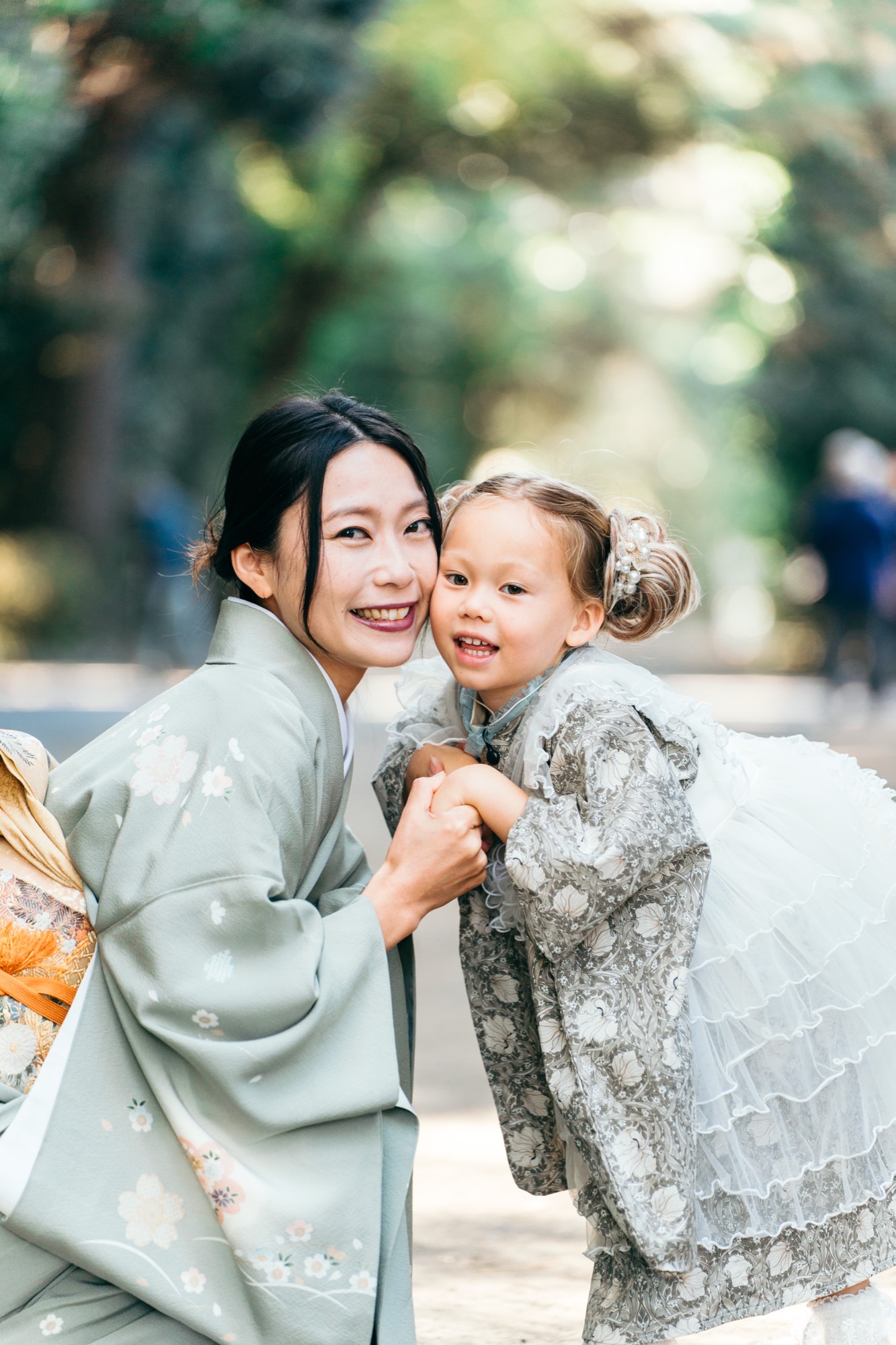 緑の着物姿のお母様と頬を寄せ合って笑う、七五三・3歳の女の子