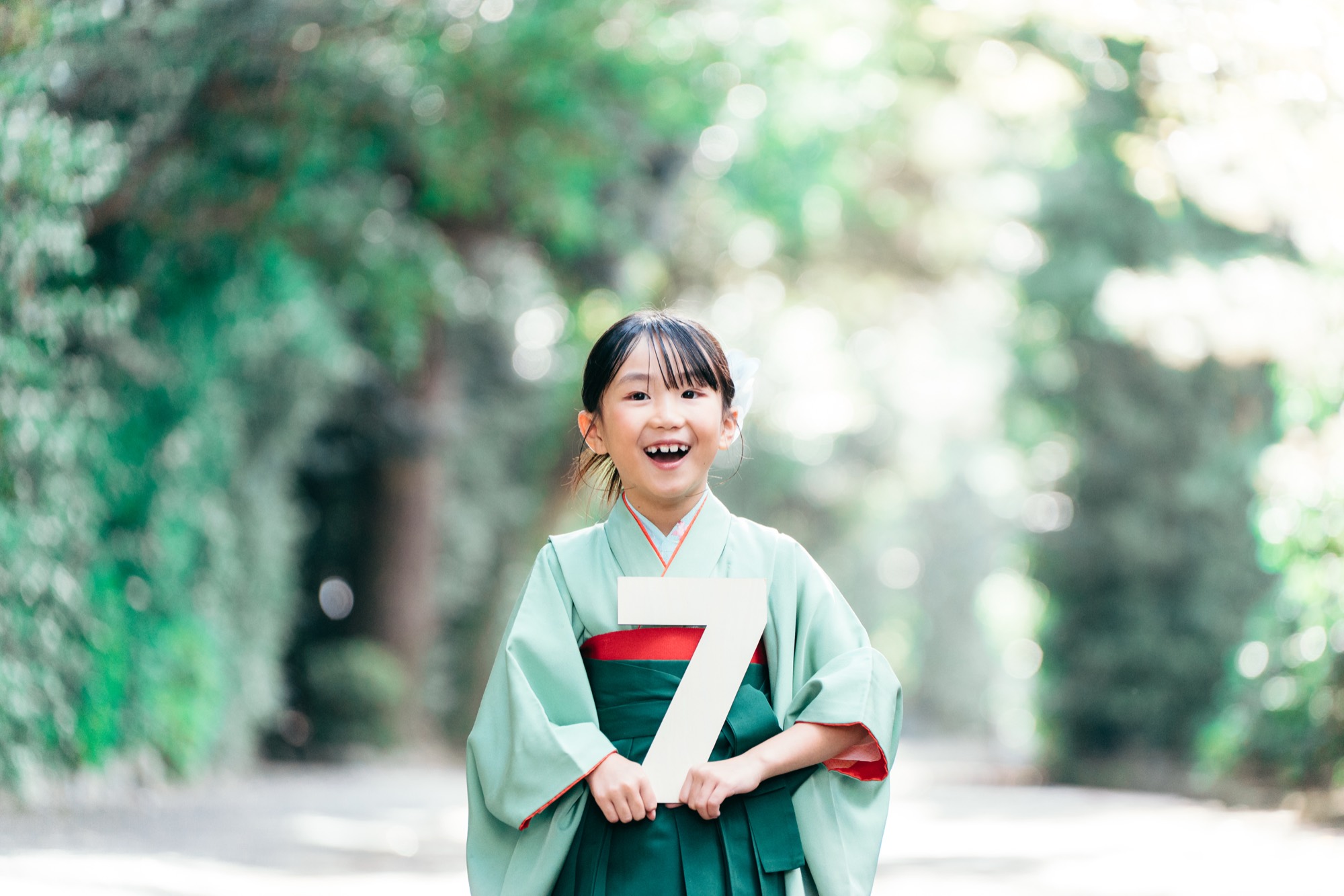 「7」の数字を持って満面の笑顔を見せる、袴姿の7歳の女の子(寒川神社の七五三)