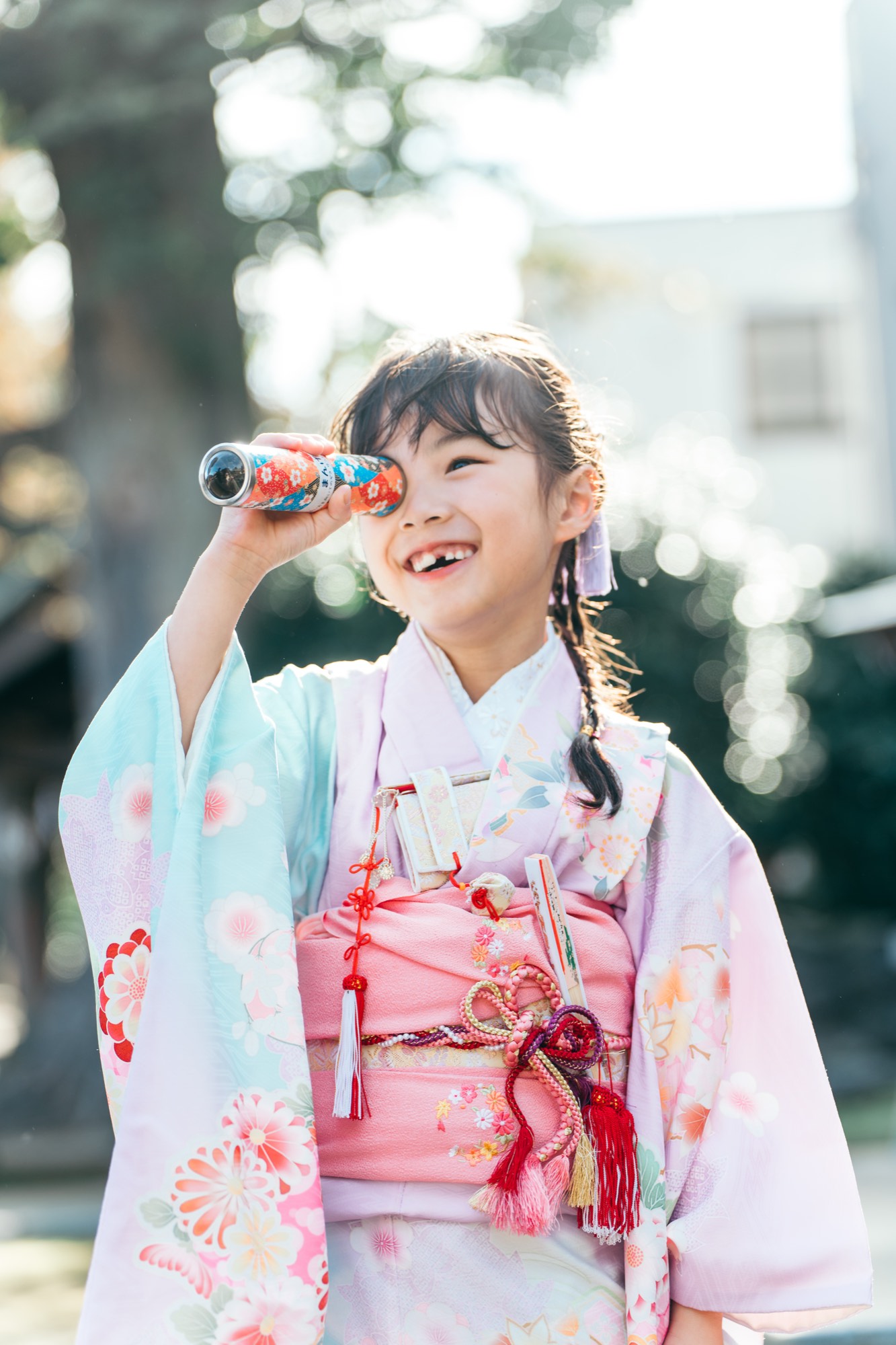 やわらかな光のなか、万華鏡をのぞいて笑う七五三・7歳の女の子（徳丸北野神社）