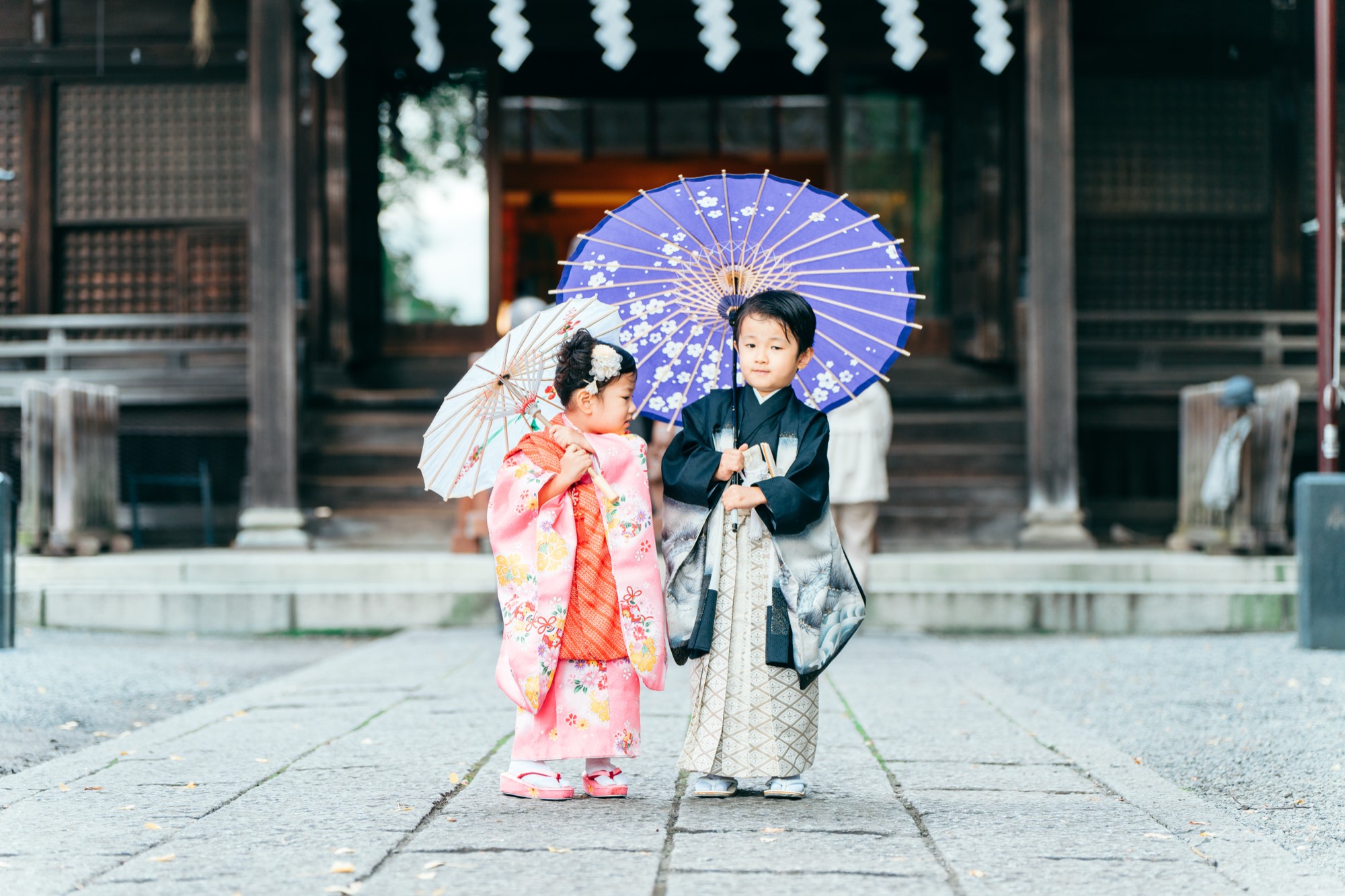 谷保天満宮の拝殿前で和傘を持つ七五三のごきょうだい(5歳の男の子と3歳の女の子)